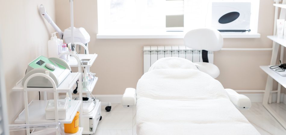 Minimalist medspa treatment room with white aesthetic equipment and procedure bed
