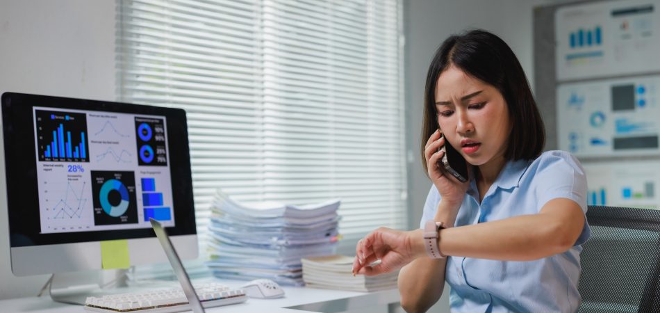 Asian businesswoman stressed by overwhelming work, checking time and talking on phone
