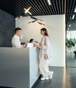 Young woman standing near the customer reception desk and looking at the terminal