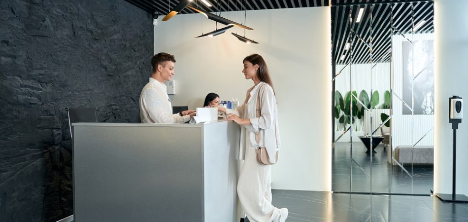 Young woman standing near the customer reception desk and looking at the terminal